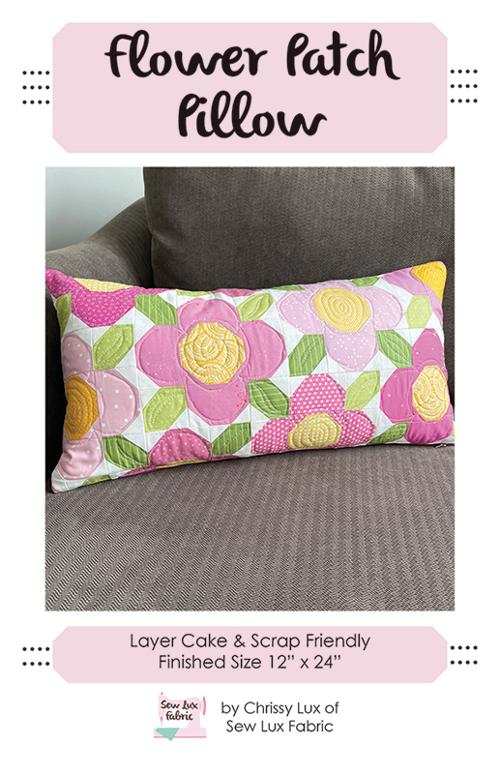 Flower Patch Pillow with pink and yellow floral quilted design on gray couch 12x24 inches