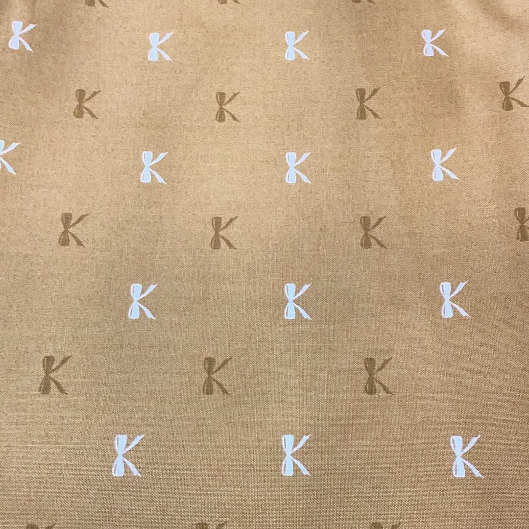 Sale Backing BB23 fabric with brown background and repeated white and dark brown "K" pattern