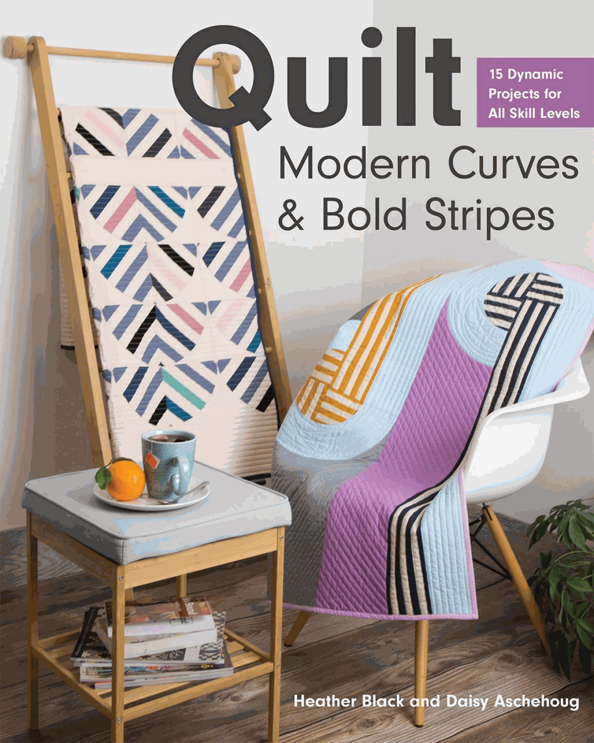 Modern quilt patterns featuring curved piecing and bold stripes displayed on chair and wooden rack