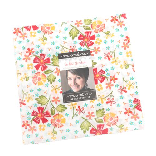 In the Garden Layer Cake fabric squares with warm floral patterns by Corey Yoder for Moda