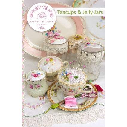 Vintage teacups and jelly jars used as decorative pincushions with floral patterns and sewing pins