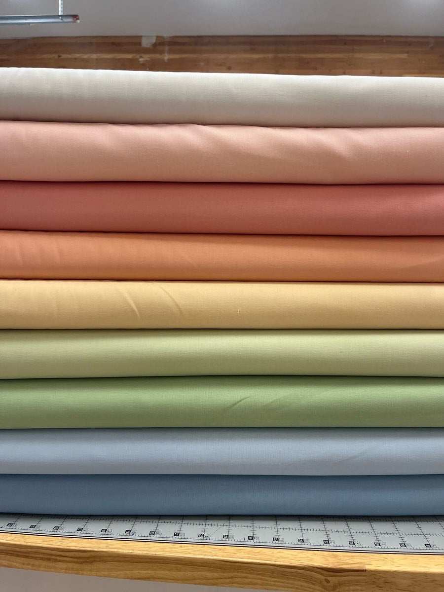 Bundle of 9 Coordinating Bella Solids fabric in half-yard increments from Moda stacked in soft pastel colors