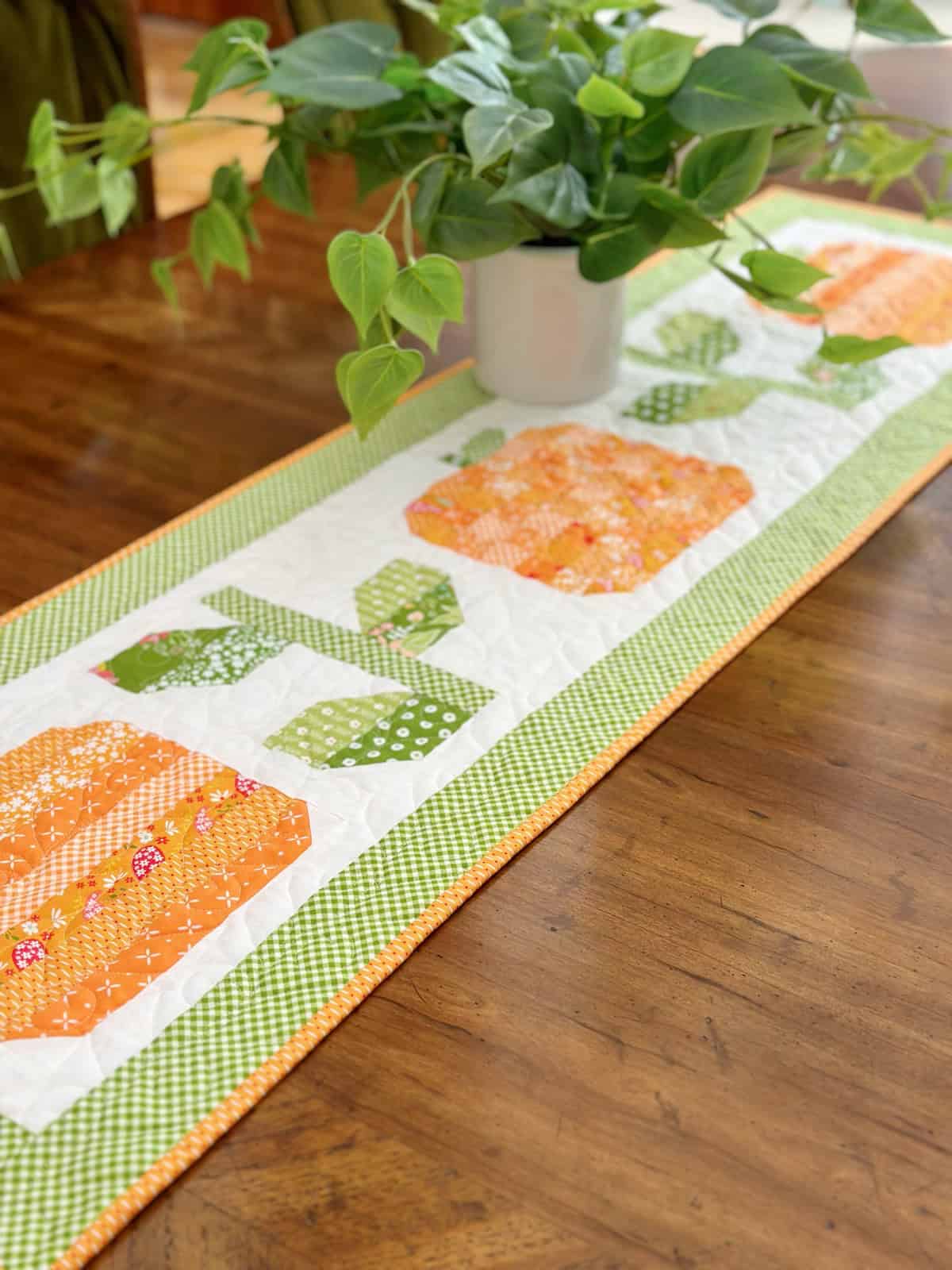 Pumpkin & Vine Table Runner with orange pumpkin and green vine quilted fabric on wood table