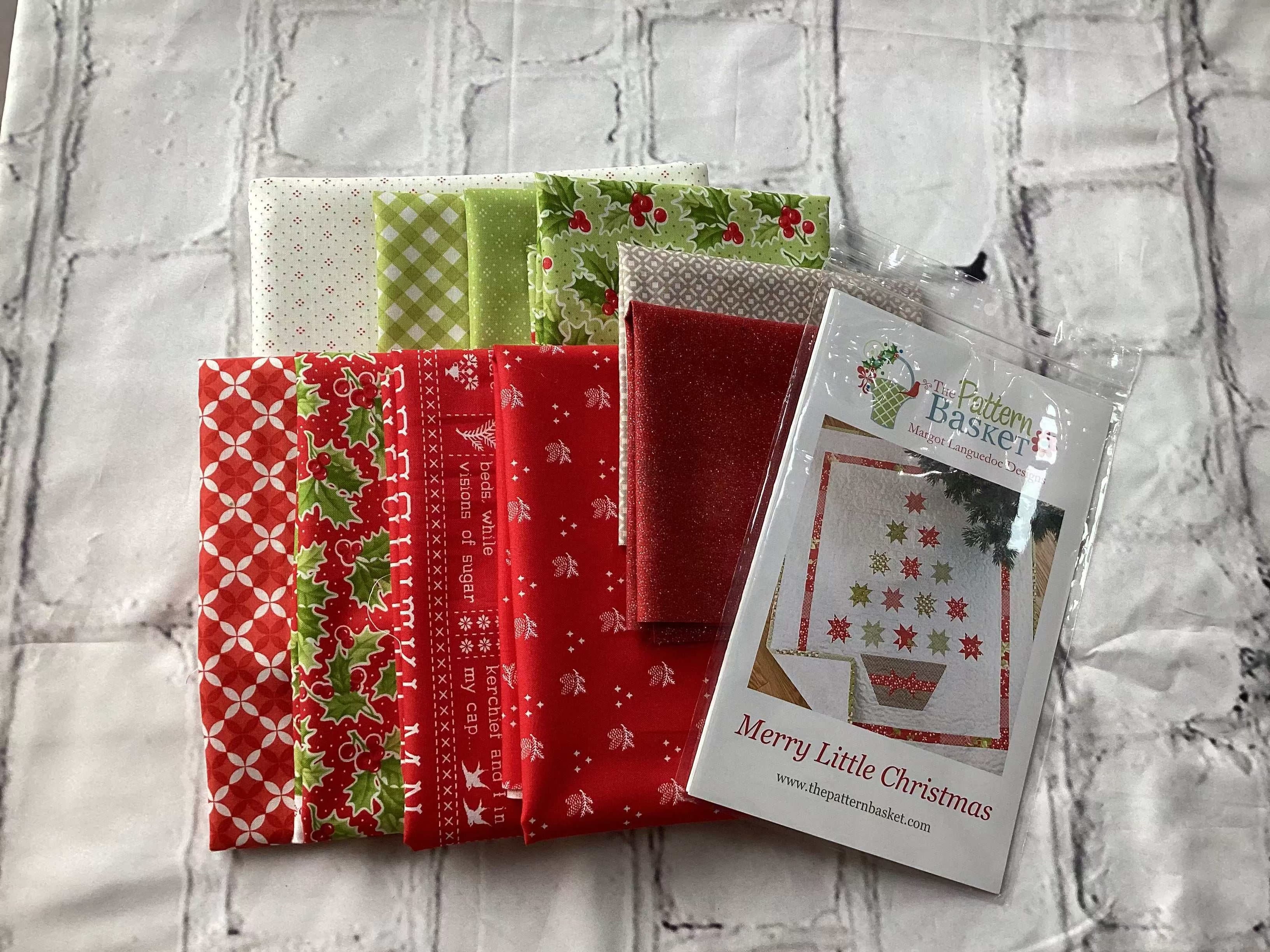 Merry Little Christmas Kit with red and green holiday fabric bundles and quilt pattern packet on white background