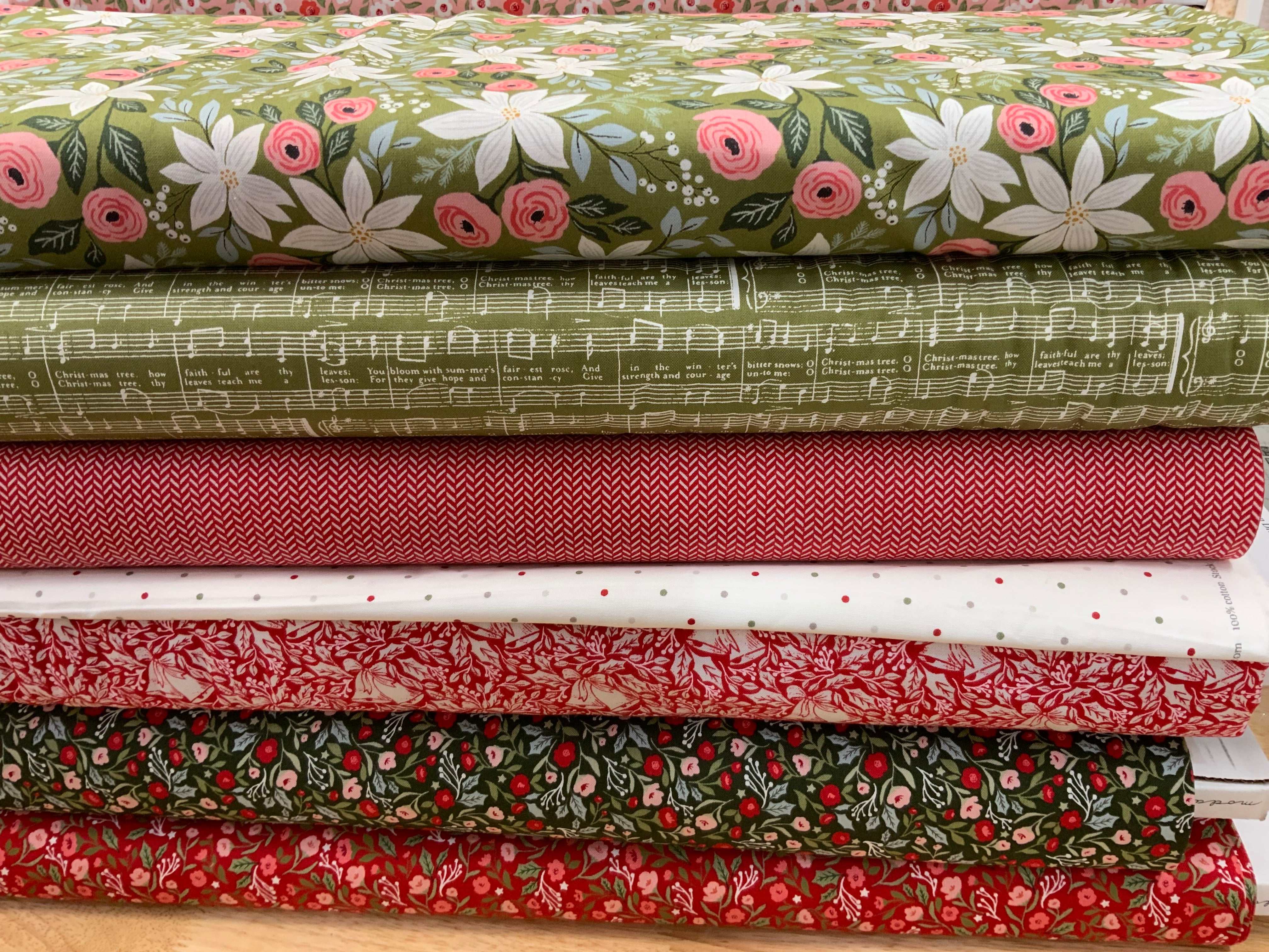 Stack of colorful floral and patterned fabrics included in the M50 Island Hopping Kit curated by Bella Rose Quilts