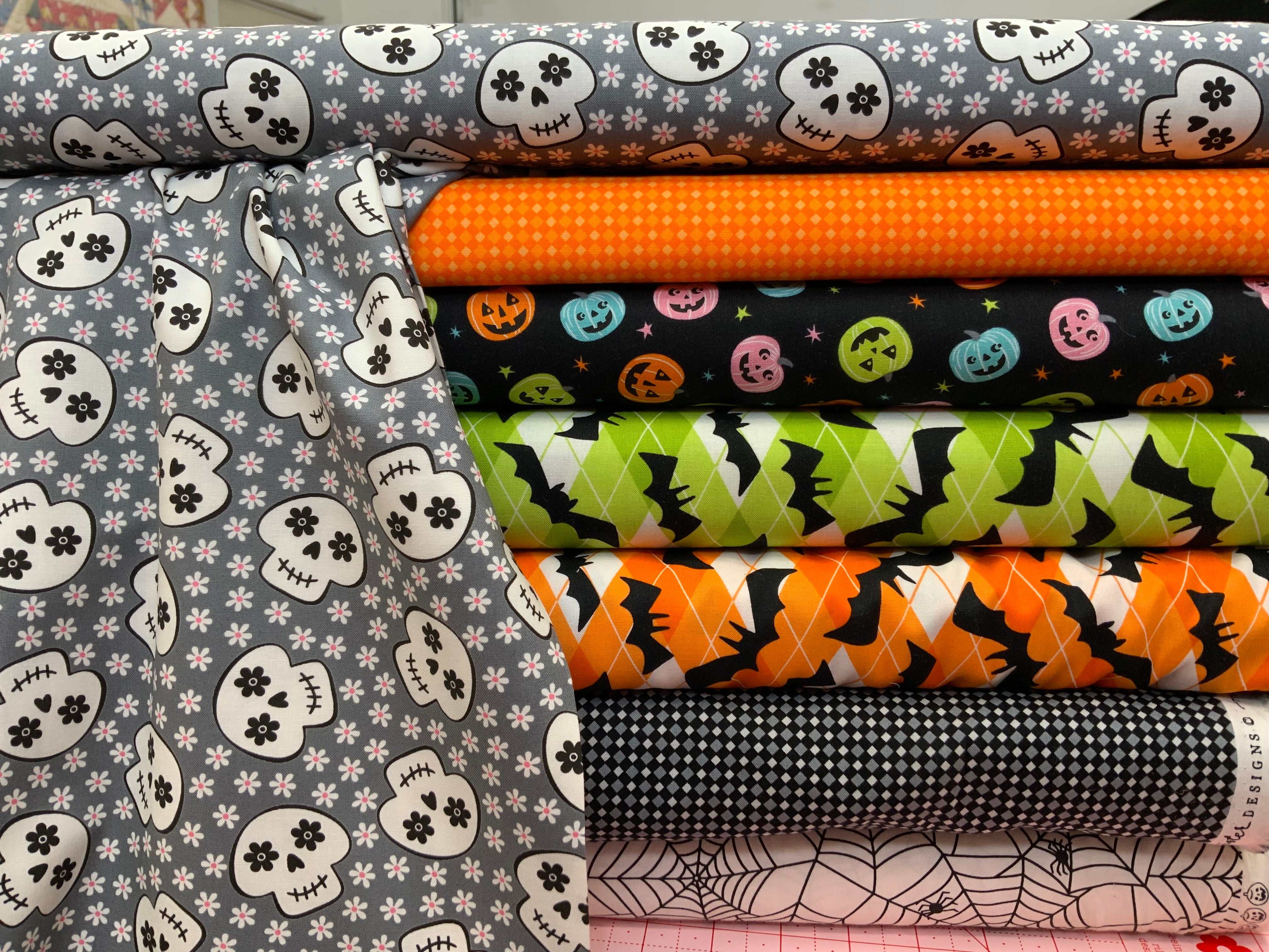 M50 Island Hopping Kit Halloween-themed quilting fabrics with skulls, pumpkins, bats, spiderwebs, and geometric patterns