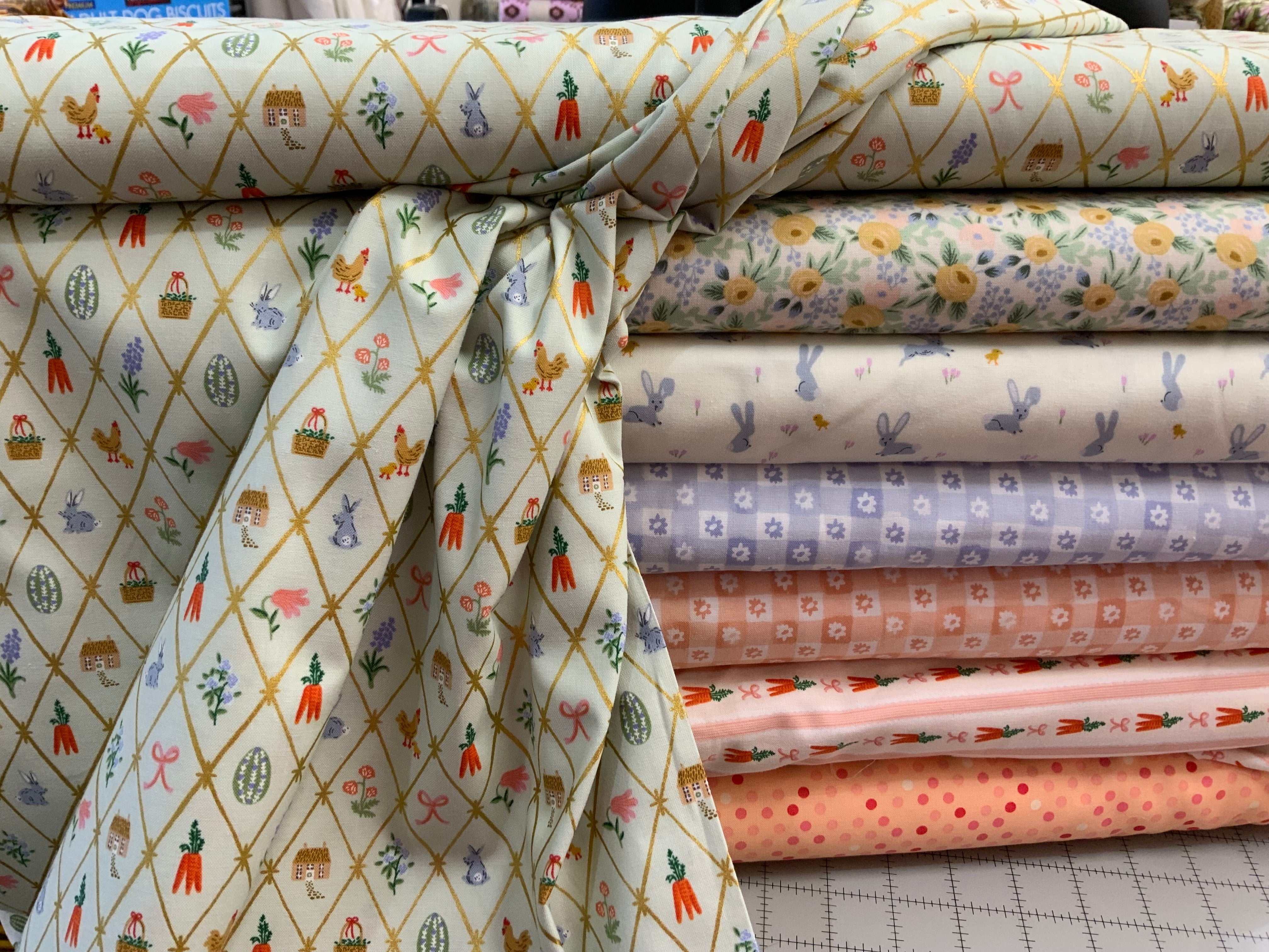 Stack of colorful quilt fabrics from the M50 Island Hopping Kit featuring floral, bunny, carrot, and polka dot patterns