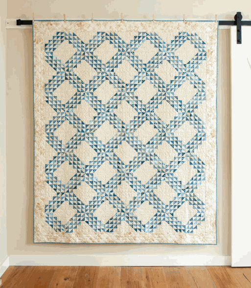 Ocean Waves Quilt Kit quilt top in blue and cream geometric pattern by Edyta Sitar hanging on wall