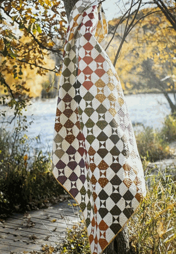 Pumpkin Crop Quilt Kit featuring fall-themed quilt in warm autumn colors outdoors