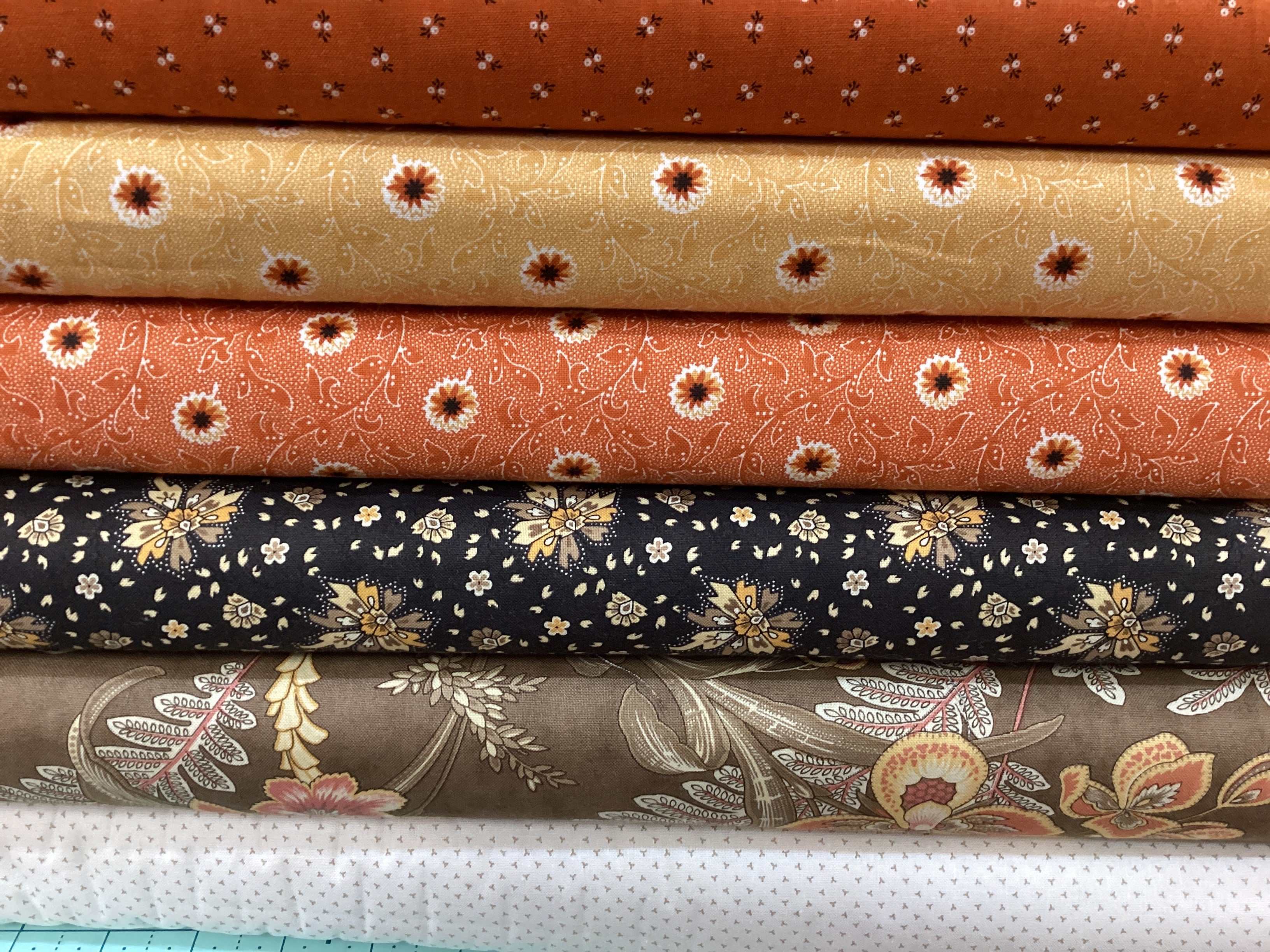 Stack of floral and patterned fabrics in warm tones from the M50 Lucky Break Kit curated by Bella Rose Quilts