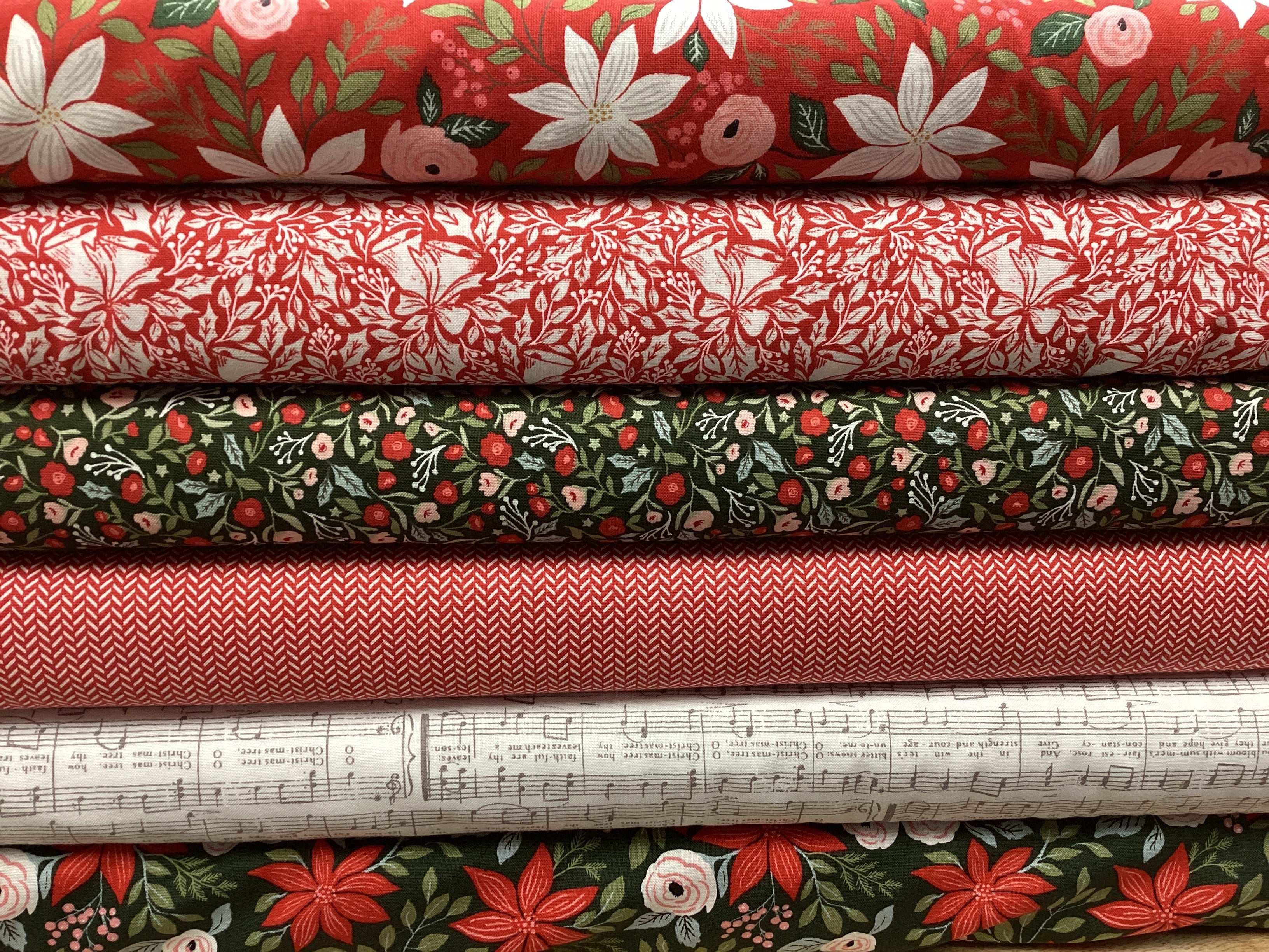 Stack of floral and patterned quilting fabrics in red, green, and white for M50 Lucky Break Kit by Bella Rose Quilts