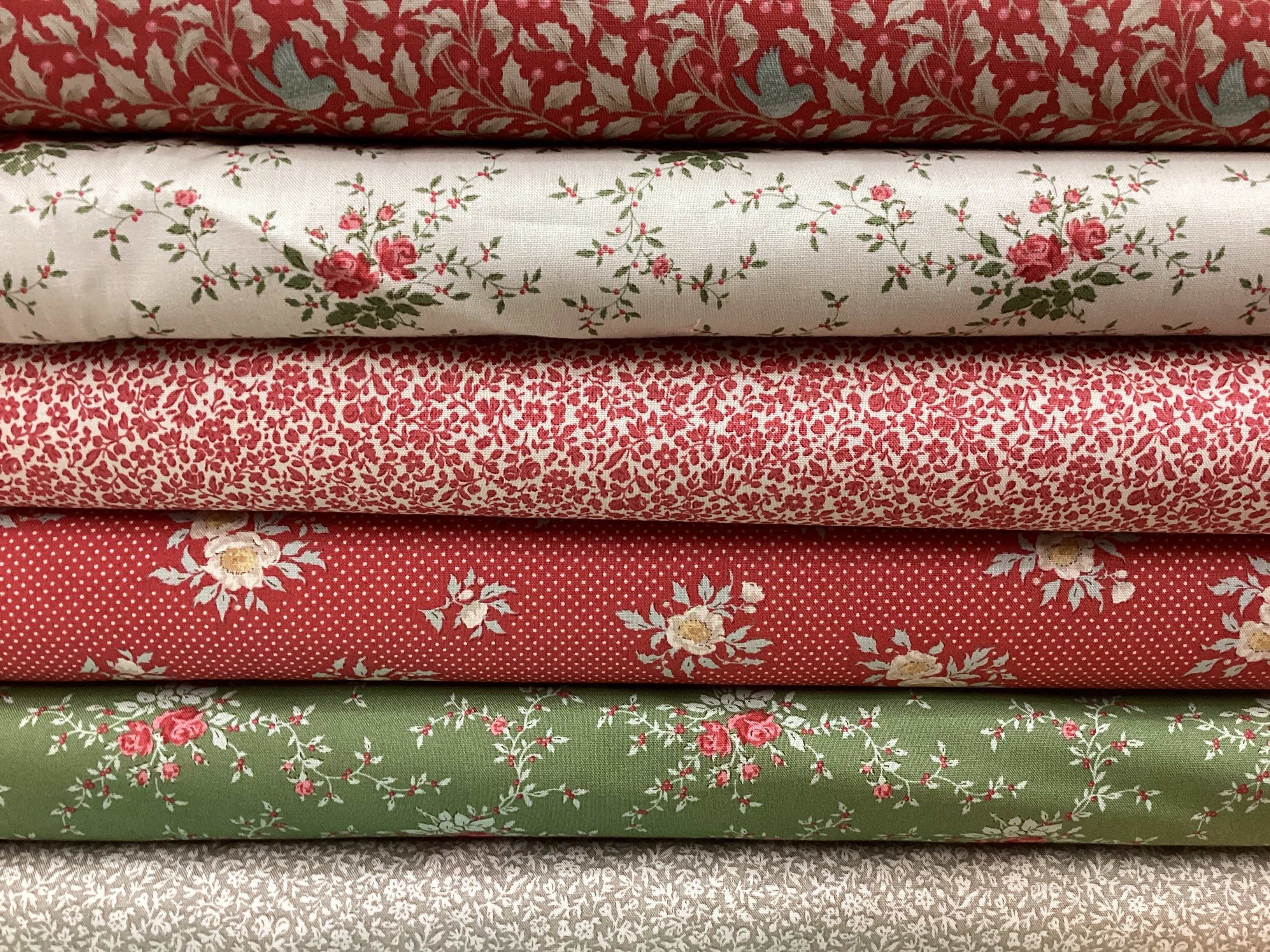 Stack of floral and polka dot fabrics in red, white, and green from the M50 Lucky Break Kit curated by Bella Rose Quilts