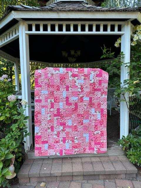 Candy Shop Jelly Roll Kit quilt with pink floral and butterfly patterns displayed in a garden gazebo