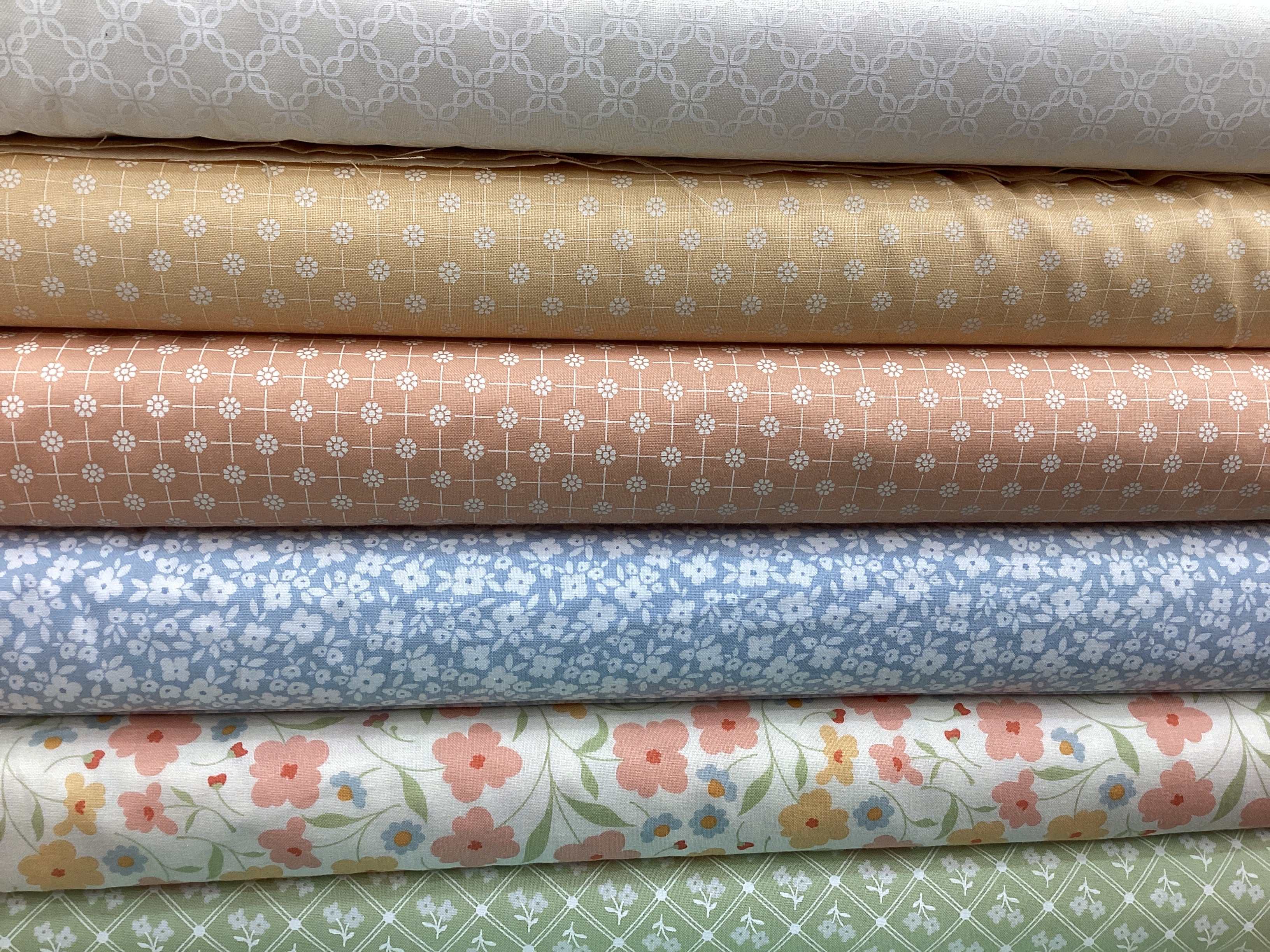 Stack of floral and patterned fabrics in muted tones from M50 Lucky Break Kit curated by Bella Rose Quilts