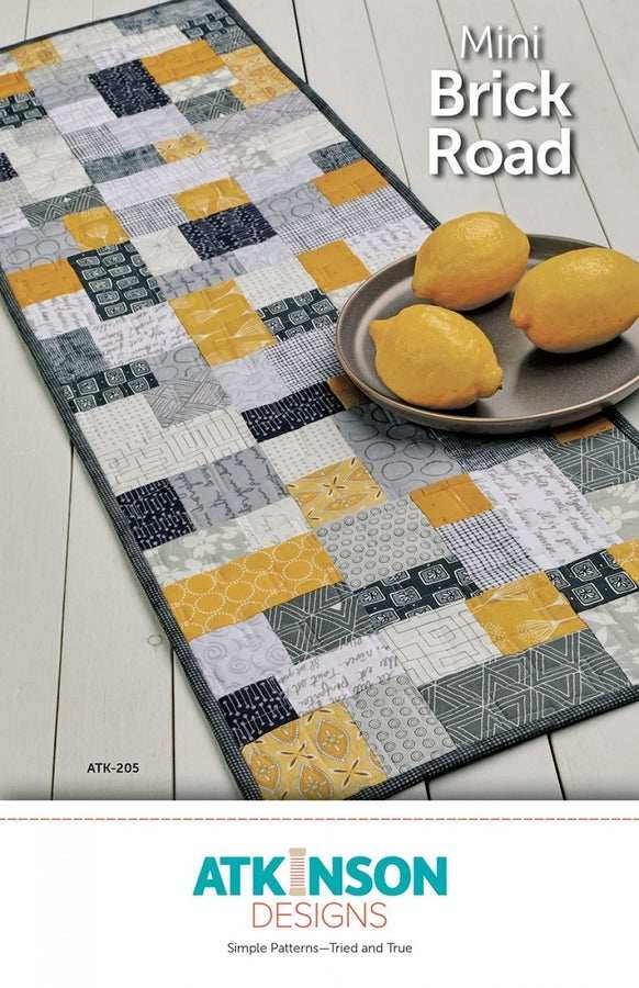 Mini Brick Road quilt pattern table runner with yellow and gray patchwork design and lemons on plate