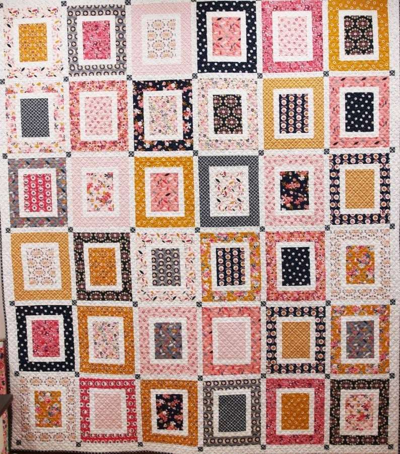 Front & Center Quilt Kit featuring colorful floral square patterns with pink, black, mustard, and white fabrics measuring 81” x 93”