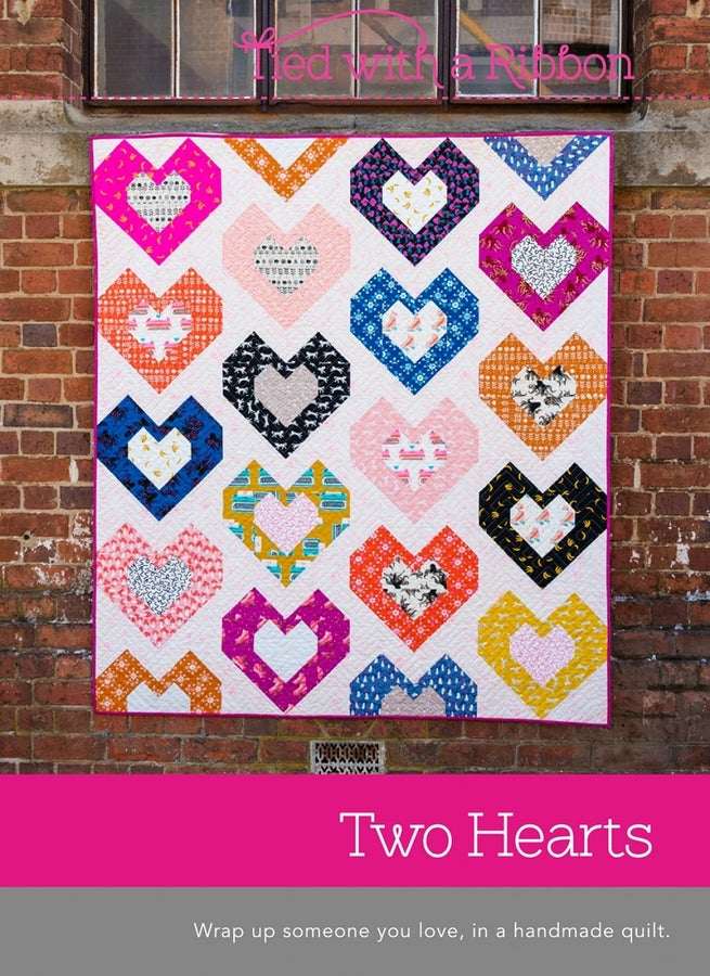 Two Hearts handmade quilt with colorful heart patterns by Creative Abundance displayed on a brick wall