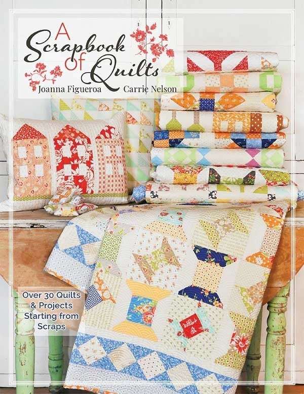 A Scrapbook Of Quilts book cover with colorful quilt patterns and fabric stacks on a wooden chair