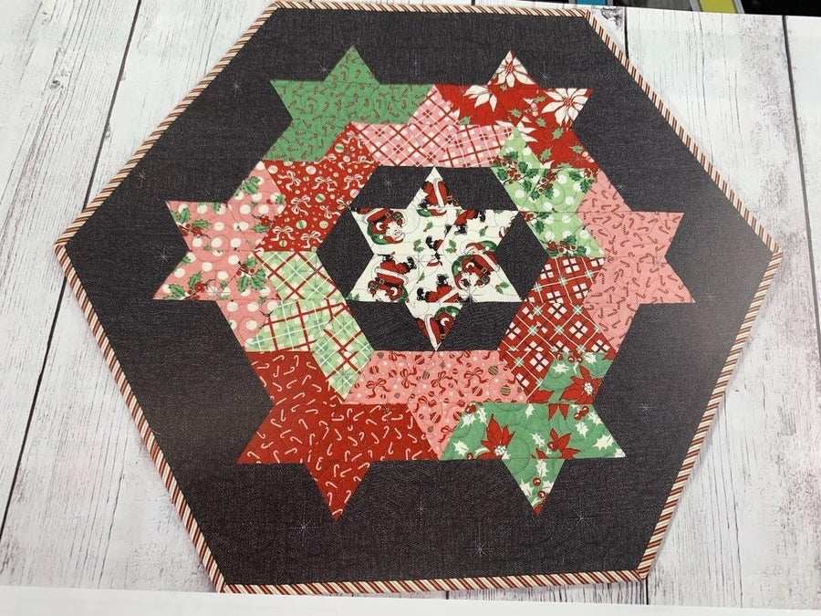 Queensbury 24x26" quilted table topper with festive patterned stars on dark background