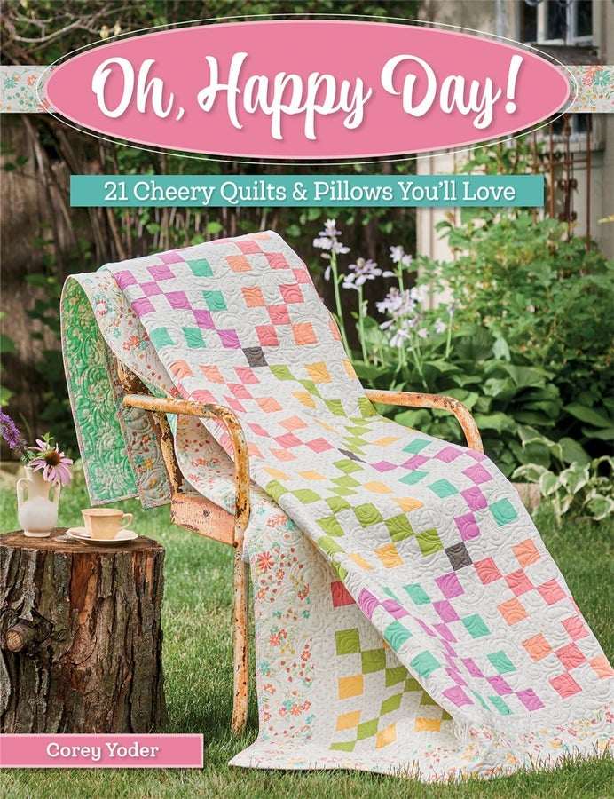 Oh Happy Day quilt draped over chair in garden with colorful patchwork pattern