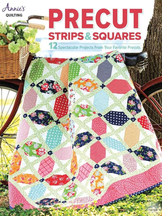 Colorful quilt made from precut strips and squares draped over a bicycle outside next to a tree and basket