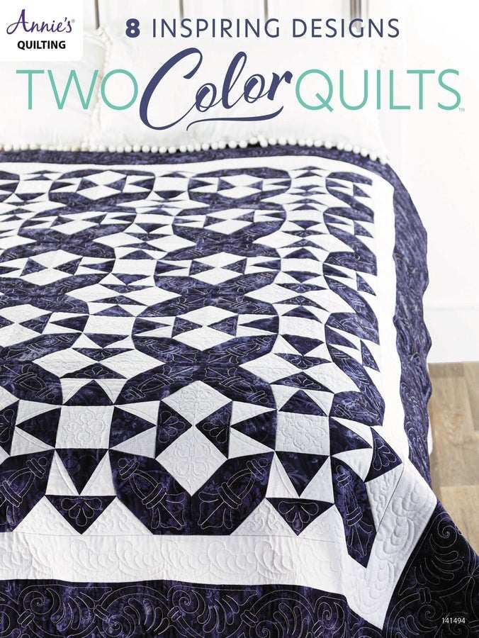 Two-color quilt with intricate navy and white geometric patterns on bed