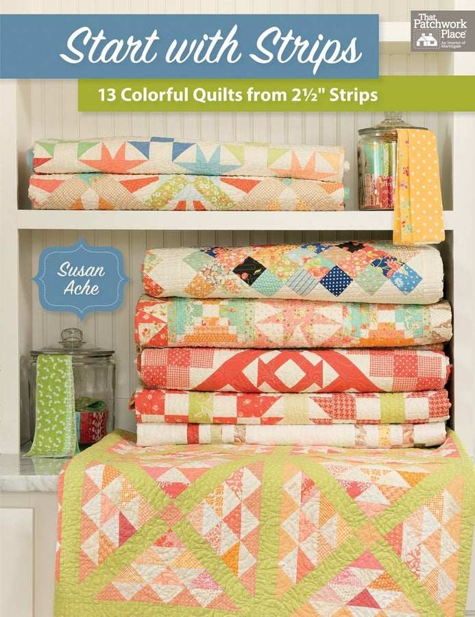 Colorful quilts made from 2.5-inch strips by Susan Ache shown stacked and folded on shelves