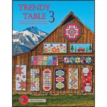 Quilted table runner designs from Trendy Table 3 by Anka's Treasures displayed on rustic barn with mountain backdrop