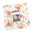 In the Garden Layer Cake fabric squares with warm floral patterns by Corey Yoder for Moda
