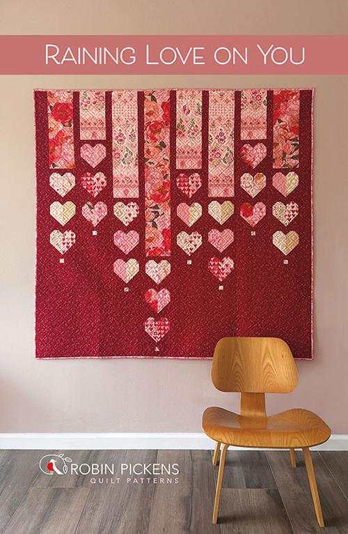 Raining Love on You quilt pattern with heart and peony design by Robin Pickens hanging above wooden chair