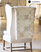 Gentle Kisses Quilt Kit throw quilt with vintage linen fabric draped over beige armchair