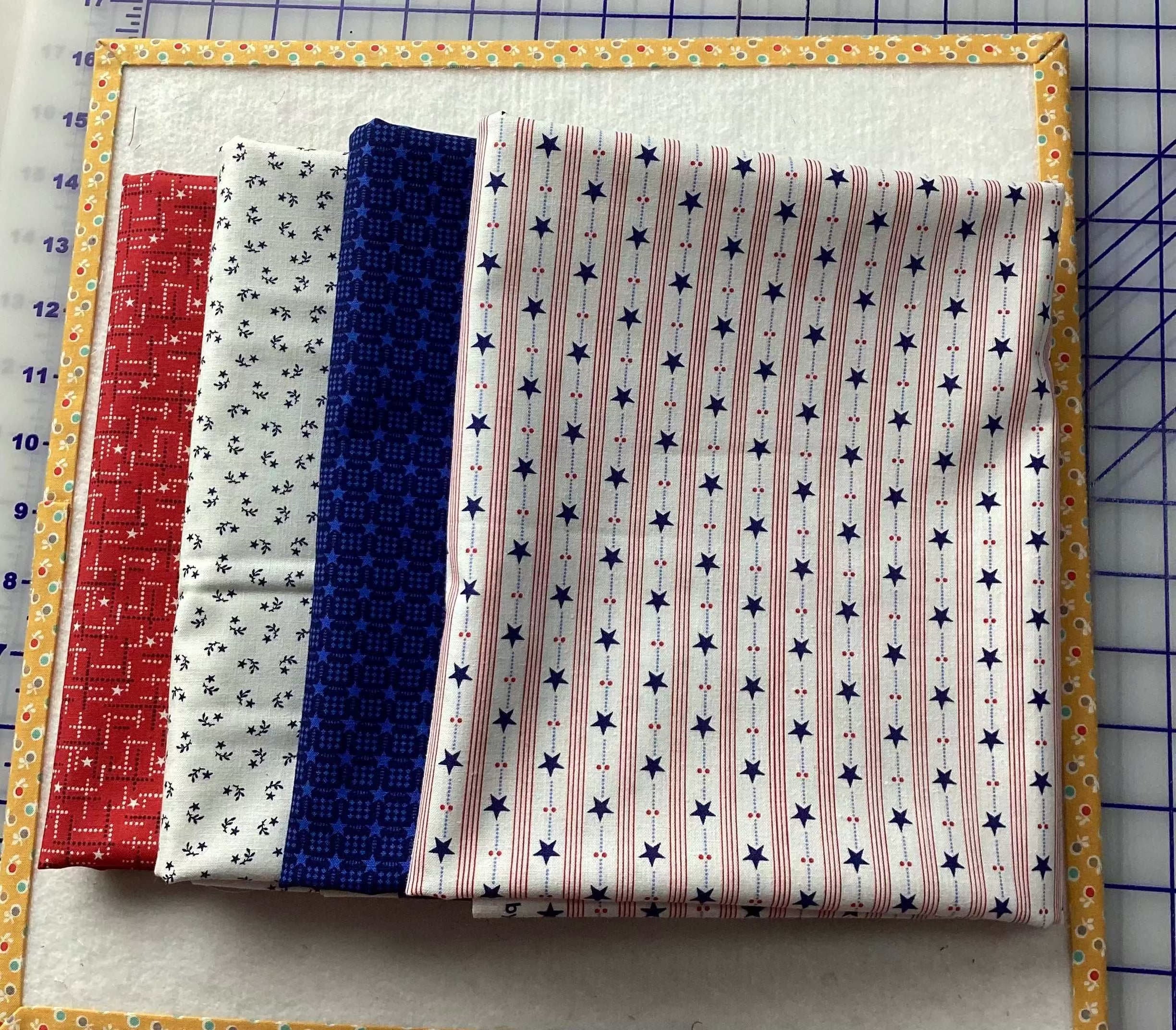 Stack of four one-yard fabric pieces in red, white, and blue patterns for 4-YARD QUILT