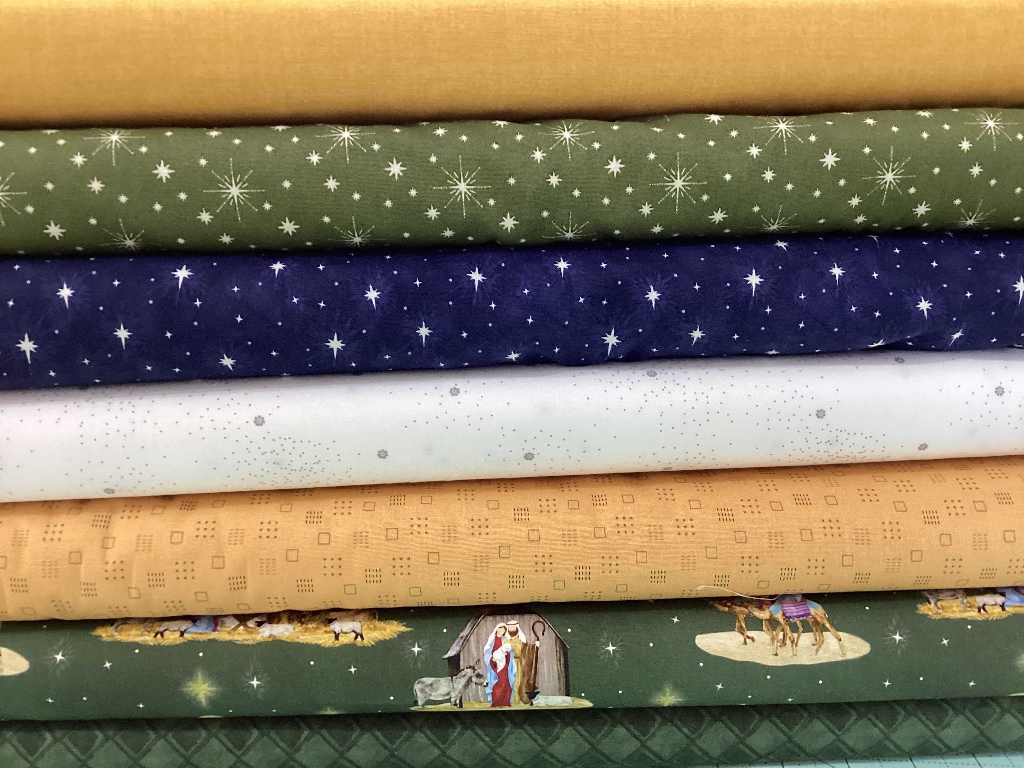 M50 Island Hopping Kit fabrics featuring star patterns, neutral tones, and nativity scenes by Bella Rose Quilts