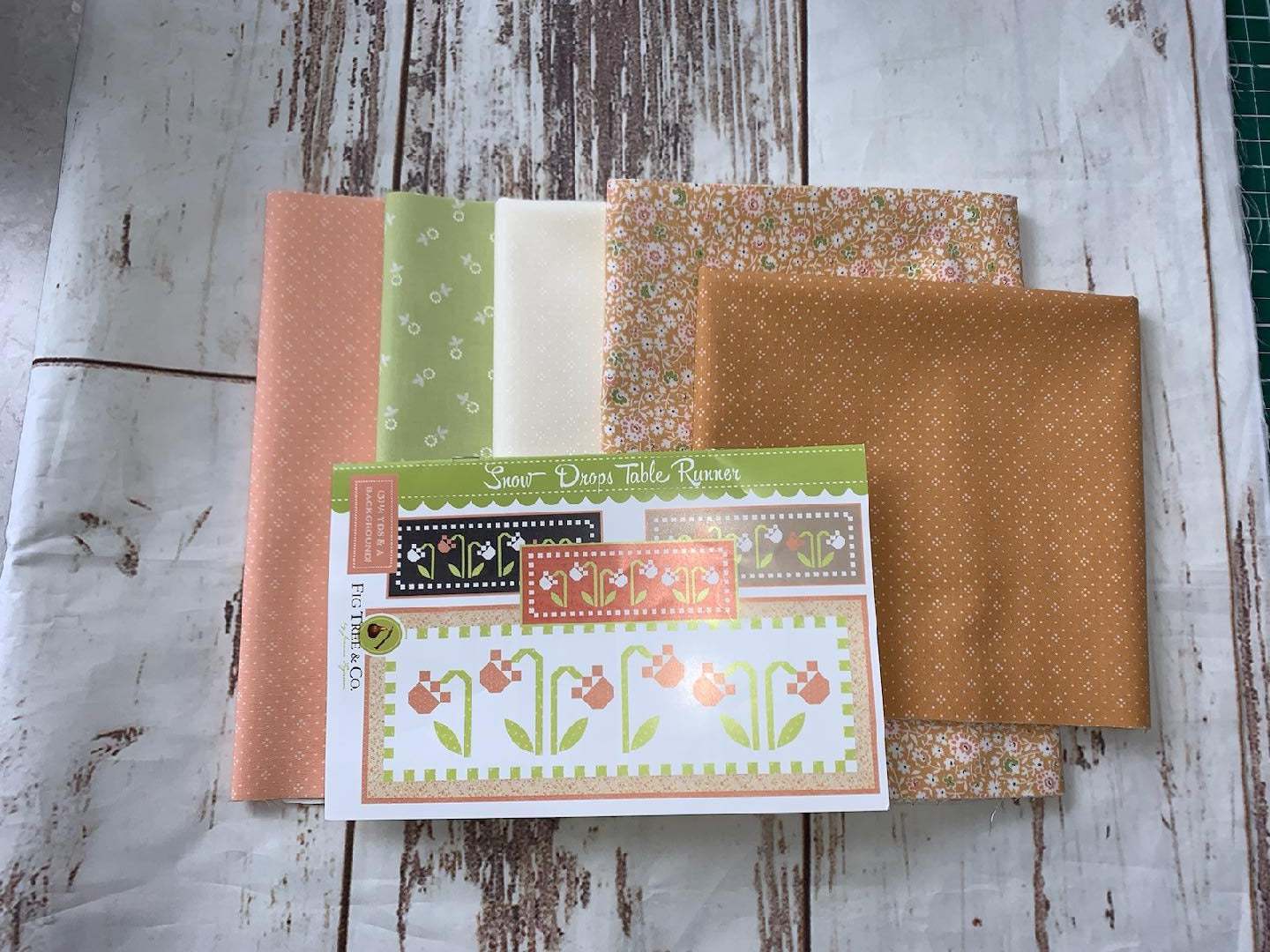 Snow Drops Table Runner kit with fabric and pattern by Fig Tree & Co. on wooden background